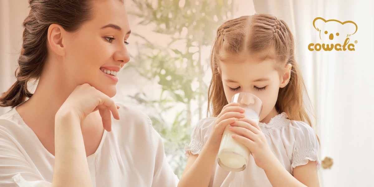 Mother watching child drink Cowala milk